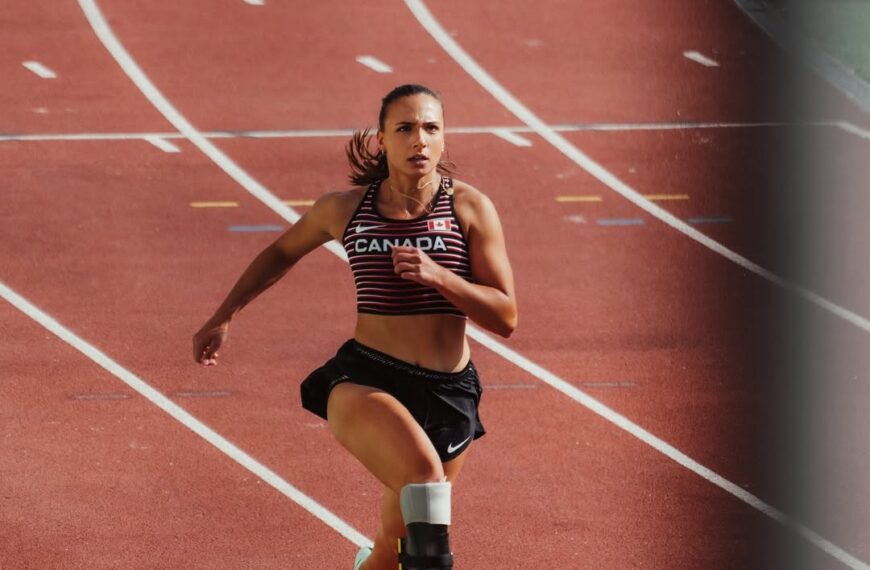 Canadian Paralympic sprinter Marissa Papaconstantinou running on track with blade prosthetic in national team gear